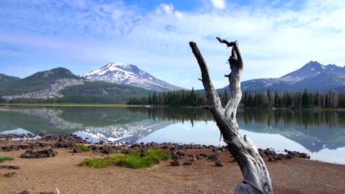 Gorgeous Oregon lake reflects mountainside under white clouds on summer vacation