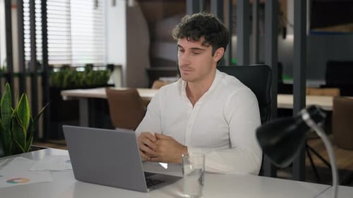 Young Adult Man Teleconferencing in Modern Office