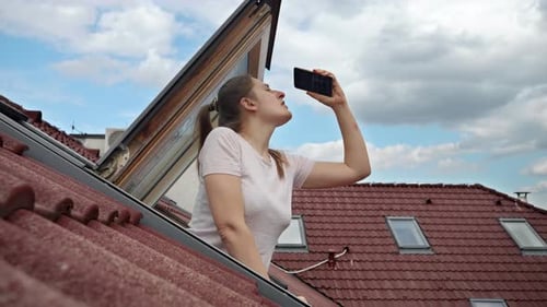 Young Woman Seeking Cell Signal from Rooftop Skylight