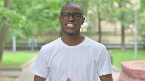 Interagierender junger afrikanischer Mann, der für Video-Chat im Freien spricht