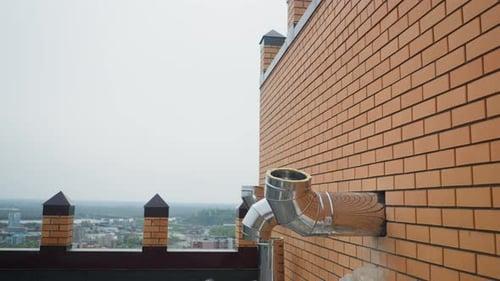 Outer Shiny Steel Ventilation Pipes in Brick Wall of Building