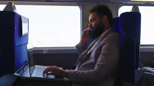 Bearded Man Working on Train With Laptop
