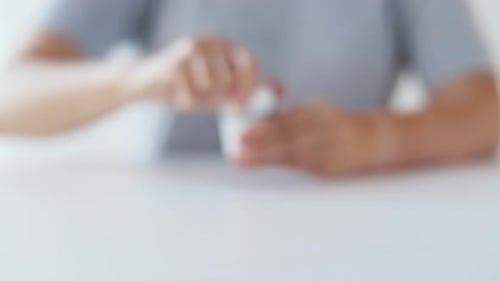 Woman Opens Medicine Bottle at Table Indoors