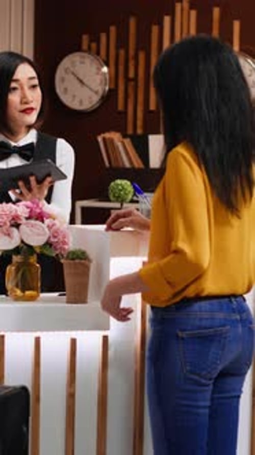 Vertical Video Hotel Guest Signing for Room Registration on Tablet at Front Desk