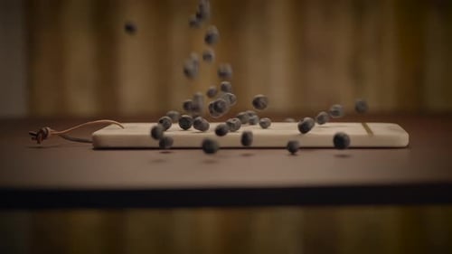 Blueberries Falling onto a Wooden Mousetrap Indoors