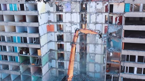 Une excavatrice atteint les hauteurs pour démonter les murs d'un vieux bâtiment.