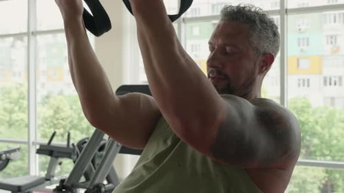 Homme mûr s'entraînant avec des sangles de suspension dans la salle de sport