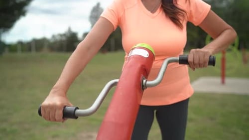 The Woman is Employing a Pedal Exercise Apparatus While at the Park - Slow Motion