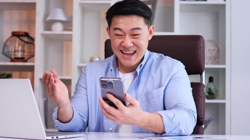 Adult Celebrates Success While Looking at Smartphone