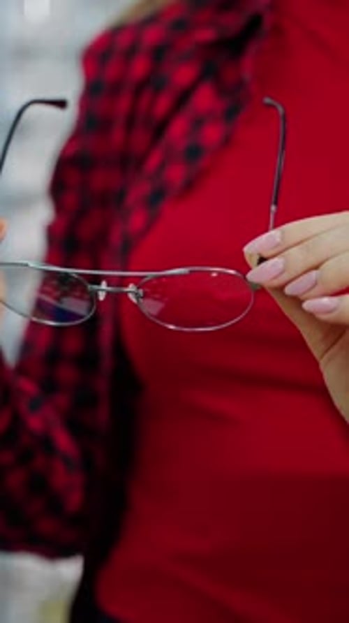 Stylish eyeglasses in woman's hands. Female buyer holding new spectacles in the optical store.