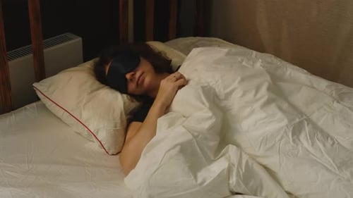 Woman in Sleep Mask Lying in Bed Preparing for Deep Sleep