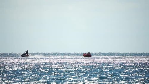 Jet Ski Pulling Inflatable Tube on Sunny Sea
