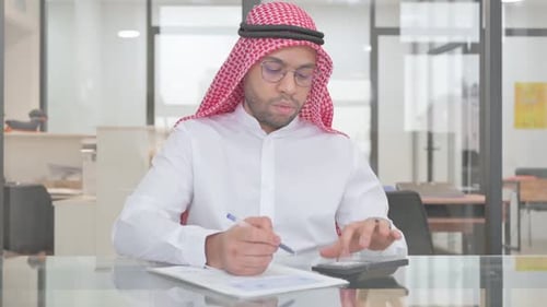 Man at Desk Calculating in Modern Office