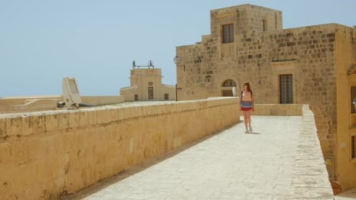 Lone Female Traveler Walking In A Medieval Castle Ruins In Europe. wide shot
