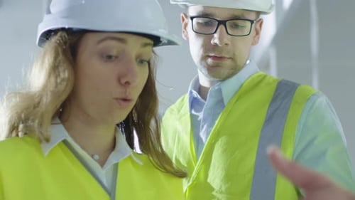 Team of Engineers in Hard Hats Having Conversation, Looking at Blueprint, inside Building Under Con