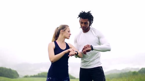 Couple checks smart watches after exercise in nature
