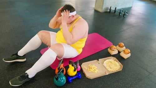 Person Doing Sit-Ups Near Junk Food in Gym