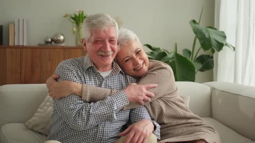 Senior Couple Embracing, Smiling on Couch Together