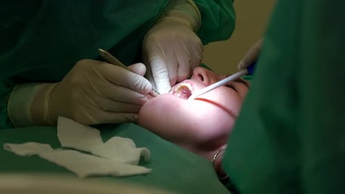 Close-up of Dentist Performing Surgery with Assistant in Dental Clinic