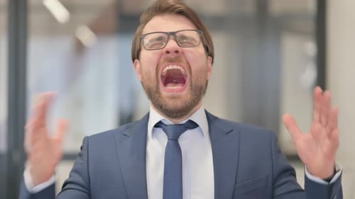 Frustrated Businessman Screaming in Anger at Workplace