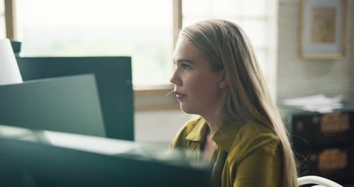 Female employee working at computer in bright modern office during daytime