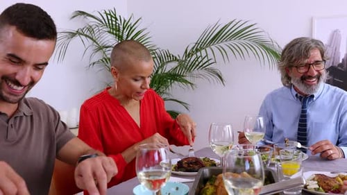 Friends Laughing and Eating Together at Dinner Table