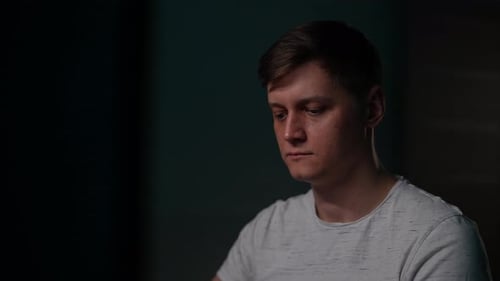 Nahaufnahme eines jungen Programmierers, der spät alleine online in einem dunklen Raum arbeitet, seriöser Hacker-IT