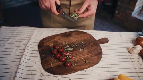 Chef cuts rosemary with scissors on wood board