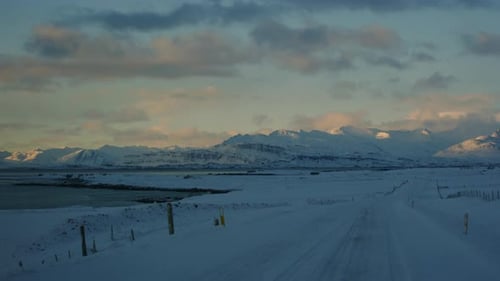 Golden sunlight over Iceland's Arctic road with snowy mountain views