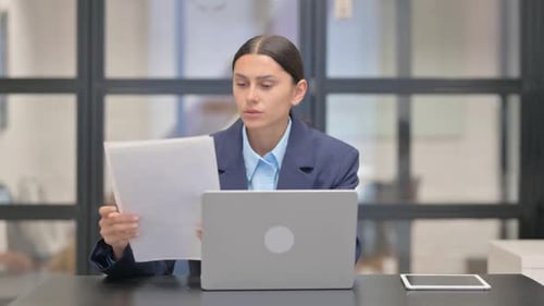 Professional Woman Reviews Documents at Office Desk