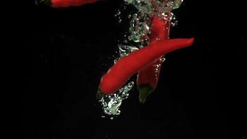 Red Chili Peppers Falling into Water, Dark Background
