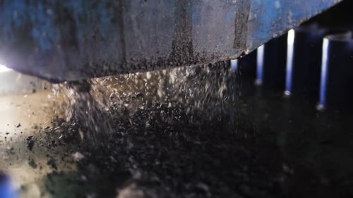 Close View Metal Machine Moves and Pours Small Tire Pieces