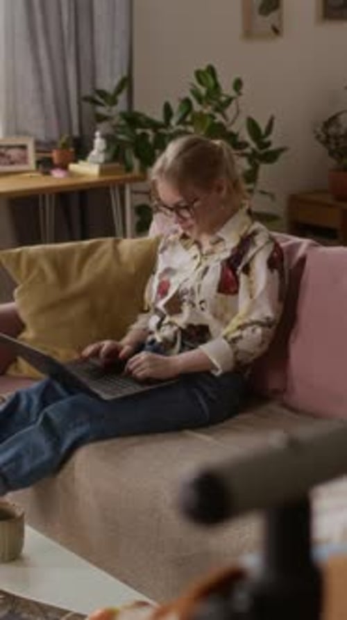 Woman Uses Laptop While Relaxing on Couch at Home