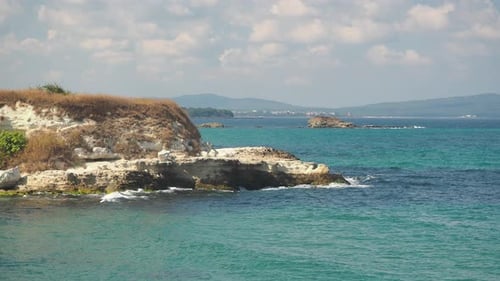 Beautiful seascape. Мighty cliffs by the ocean, rocks on shore in foreground.