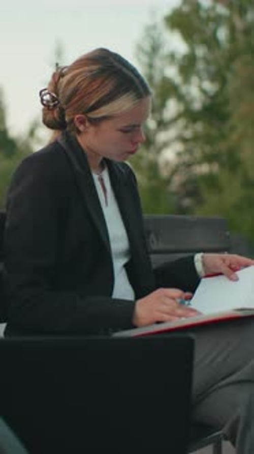 Side View Girl Focused Reading Outdoor with Book Coffee Laptop and Urban Background