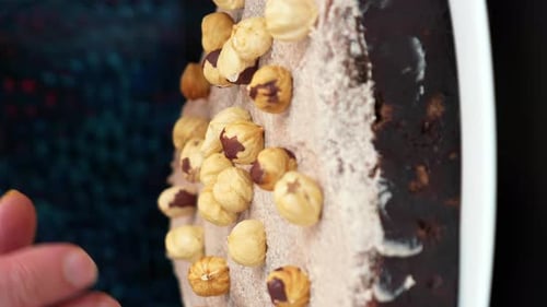 Hands Decorating Dessert with Hazelnuts