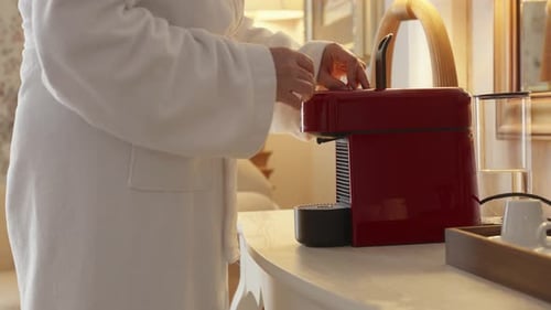 Woman in robe uses a red coffee machine
