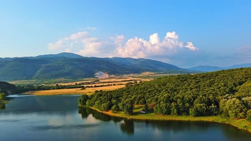Lake with Clear Water and Stone Shore in Spruce Forest with Fir Trees Against a Daytime Sky