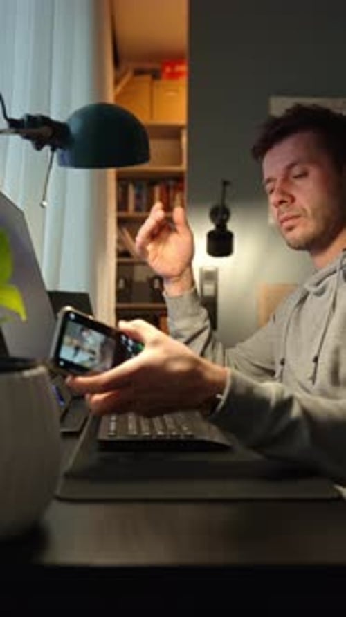 Freelancer Procrastinating at Home Office Scrolling Phone Instead of Working