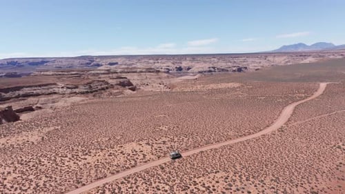 Aerial, camper van on road trip driving on vast red desert in Arizona