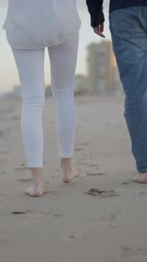 Back View of Unrecognizable Couple Feet Walking Barefoot on the Beach Sand