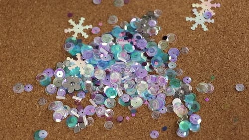Des paillettes de couleur froide tombant sur un tapis en liège. Matériel pour l'artisanat.