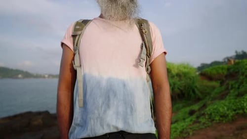 Stylish Handsome Senior Man in Tshirt Shorts Backpack with Grey Beard Sunbathes and Enjoys View of