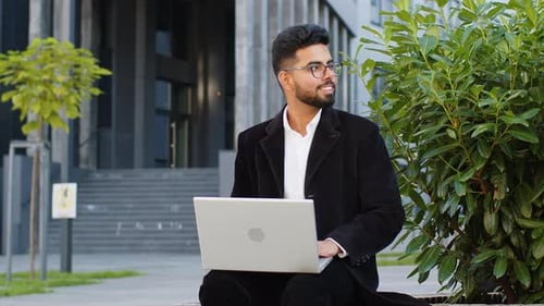 Young Adult Works on Laptop in Urban Setting