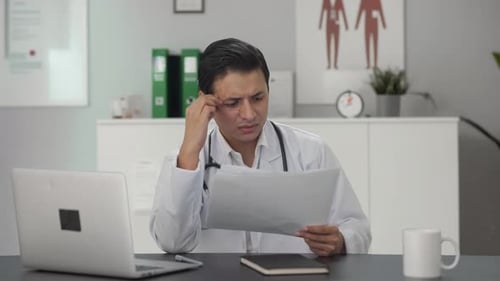 Thoughtful Doctor Reviewing Patient Paperwork in Office