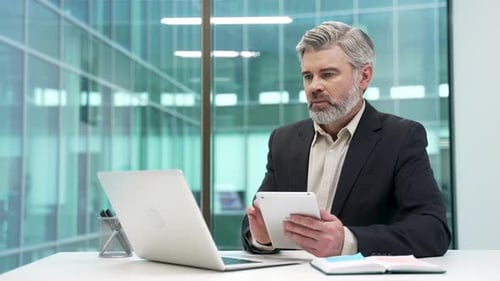 Businessman is using digital tablet sitting at desk at workplace in business office. Entrepreneur