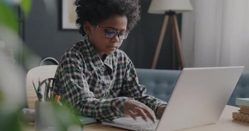 Zeitlupe eines afroamerikanischen Kindes, das mit einem Laptop arbeitet und mit einem modernen Gerät surft