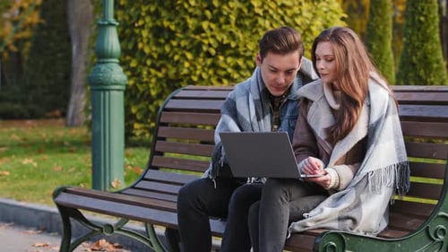 Young Adults Using Laptop on Park Bench