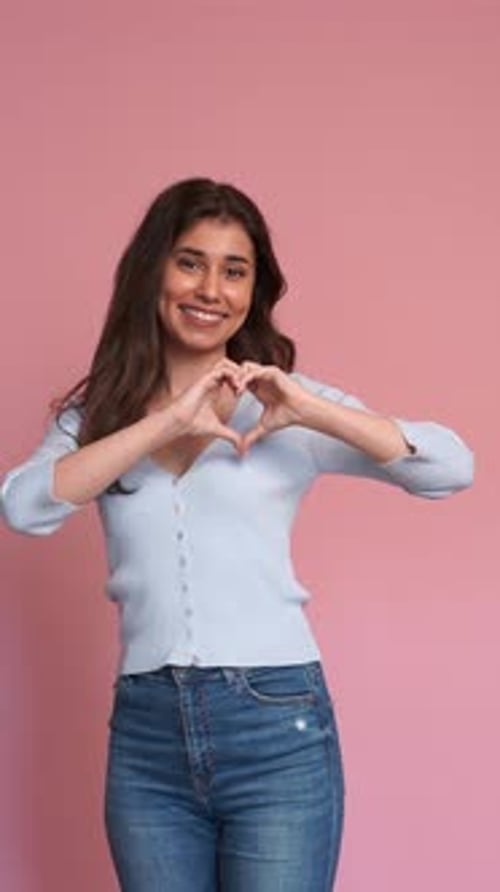 Happy Woman Makes Heart Shape with Hands