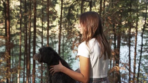 Young Woman in Casual Clothes is Sitting on Blanket at a Glade of Autumn Park Smiling Hugging and